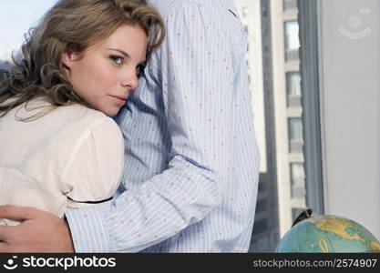 Young couple embracing each other near a window