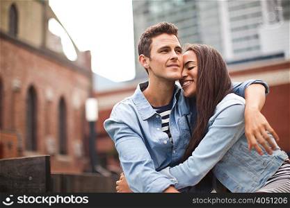Young couple embracing in city, smiling