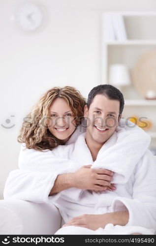 Young couple embracing in robes at home