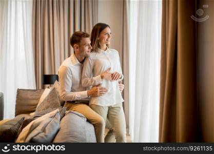 Young couple embracing standing in living room of a contemporary apartment