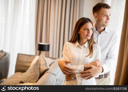 Young couple embracing standing in living room of a contemporary apartment