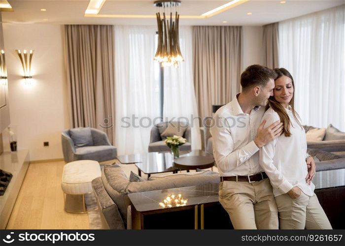 Young couple embracing standing in living room of a contemporary apartment