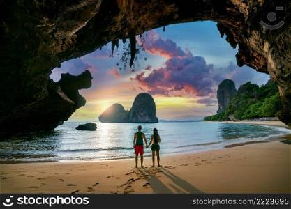 Young couple enjoying beautiful sunset at Railay beach, Krabi in Thailand.