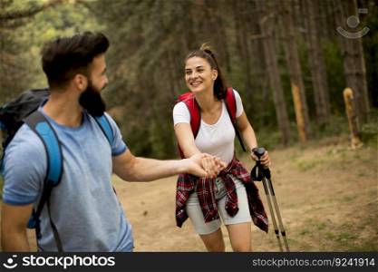 Young couple enjoying hiking in nature, holding hands and laughing. 