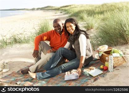 Young Couple Enjoying Picnic On Beach Together