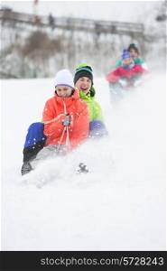 Young couple enjoying sled ride on snow covered slope