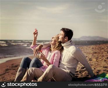 young couple enjoying time together at beach. Young Couple having fun and making soap bubbles On The Beach at autumn day colored filter