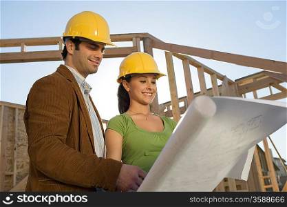 Young couple examining blueprint in construction site