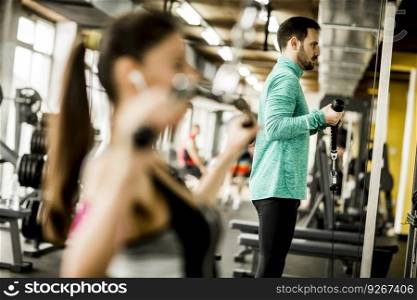 Young couple exercise bodybuilding exercises in the modern gym