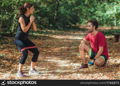 Young Couple Exercising with Elastic Resistance Band Outdoors in the Park. Young Couple Exercising with Elastic Resistance Bands  