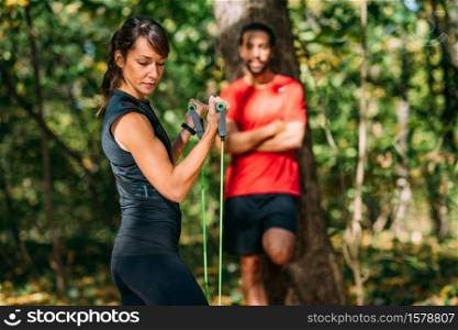 Young Couple Exercising with Elastic Resistance Bands in a Park. Young Couple Exercising with Elastic Resistance Band