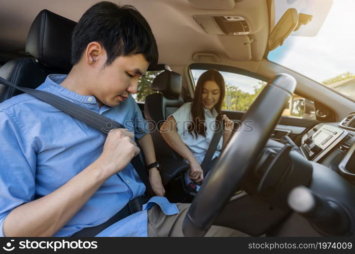 young couple fastening seat belt on before driving a car.