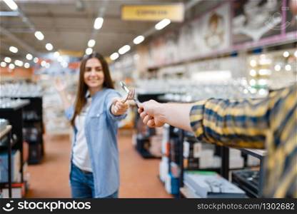Young couple fencing with a knife and fork in houseware store. Man and woman buying home goods in market, family in kitchenware supply shop. Young couple fencing in houseware store