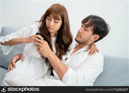 Young couple fight for TV remote on sofa in home living room in the morning.. Couple fight fot TV remote in living room.