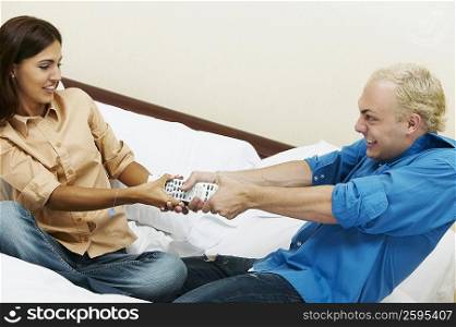 Young couple fighting for a remote control on the bed