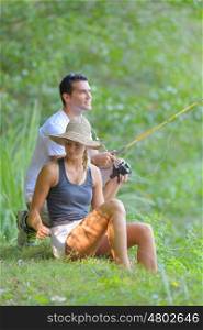 young couple fishing on the banks of the pond