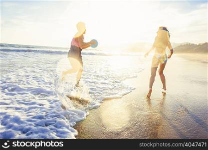 Young couple fooling around on beach, on sea, sunset