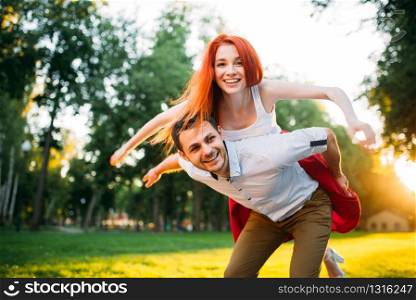 Young couple funs together in summer park. Romantic date of attractive woman and young man. Young couple funs together in summer park