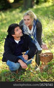 Young couple gathering mushrooms in field