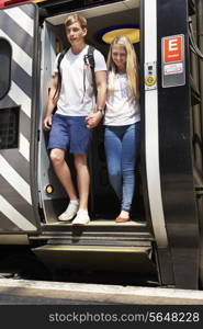 Young Couple Getting Off Train At Platform