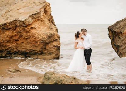 young couple groom with the bride on a sandy beach at a wedding walk