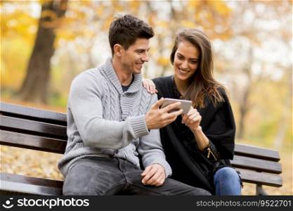 Young couple happily watching something on a smartphone in autumn park