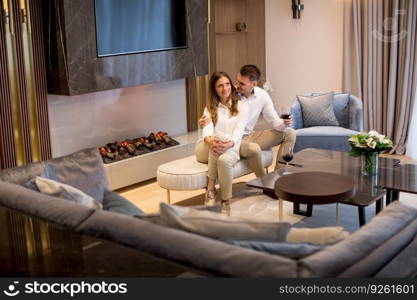 Young couple having a romantic evening with a glass of red wine at home in the luxury contemporary living room