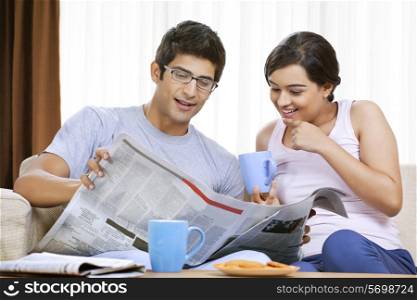 Young couple having coffee while reading newspaper