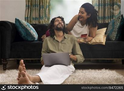 Young couple having fun during online shopping through laptop using credit card at home
