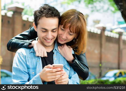Young couple having fun using application on smartphone outdoors.