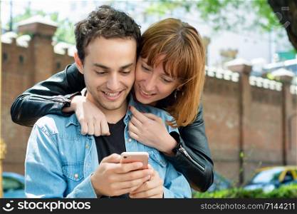 Young couple having fun using application on smartphone outdoors.