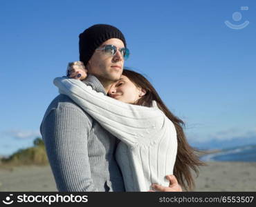 Young couple having fun walking and hugging on beach during autumn sunny day. Loving young couple on a beach at autumn sunny day