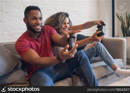 Young couple having fun while playing video games together at home.