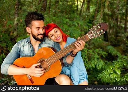 Young couple having fun with guitar in the park. Happy moments