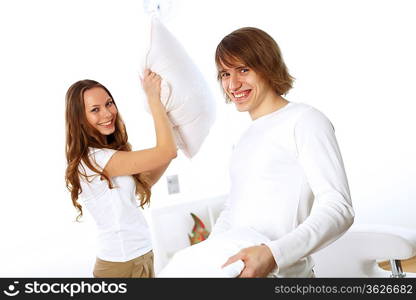 Young couple having fun with pillows at home