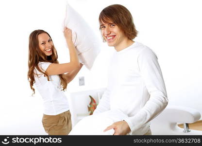 Young couple having fun with pillows at home