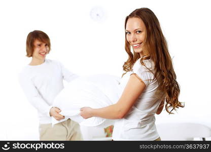 Young couple having fun with pillows at home