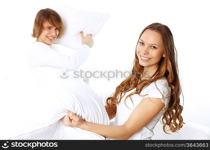 Young couple having fun with pillows at home