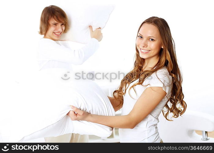 Young couple having fun with pillows at home