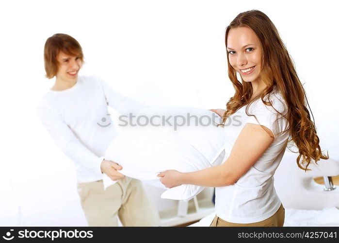 Young couple having fun with pillows at home