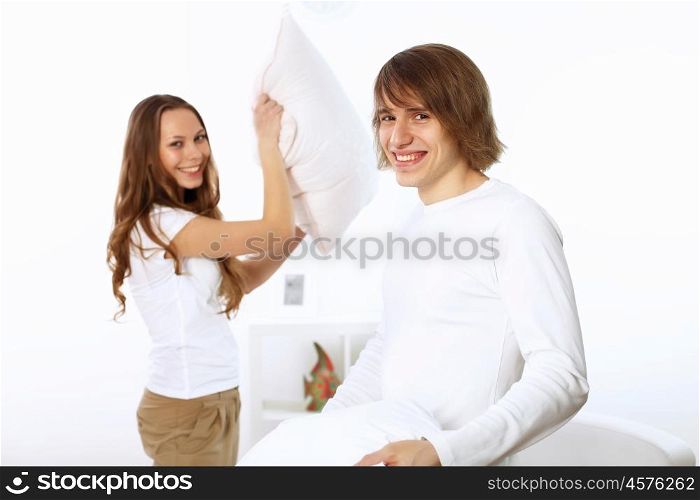 Young couple having fun with pillows at home
