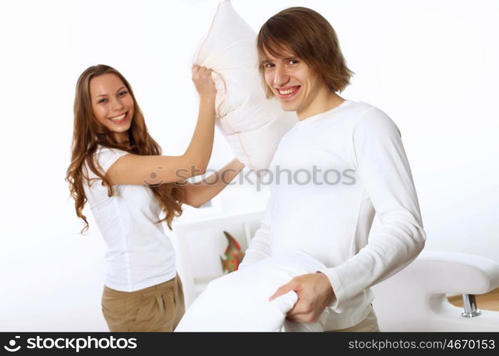 Young couple having fun with pillows at home