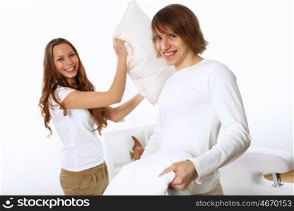 Young couple having fun with pillows at home