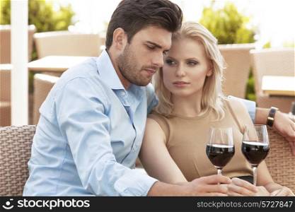 Young couple having red wine at outdoor restaurant
