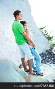Young couple having romantic minutes on the rocky coast, sunny morning.