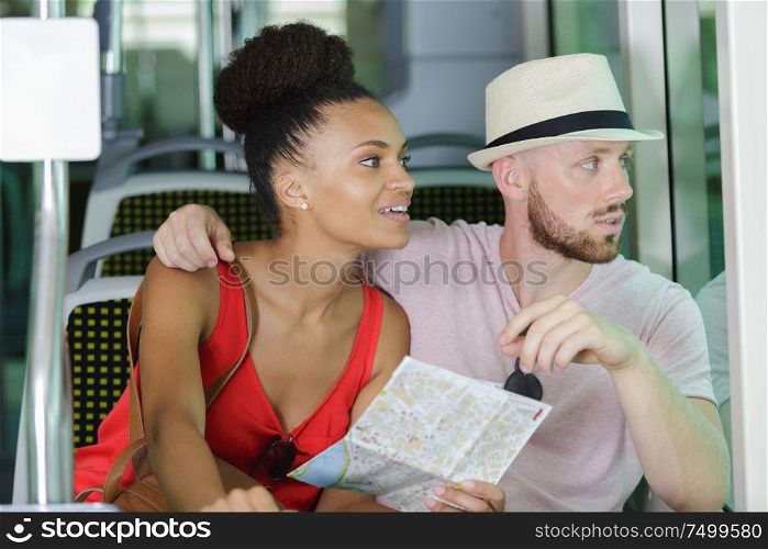 young couple holding a map while travelling on public transport
