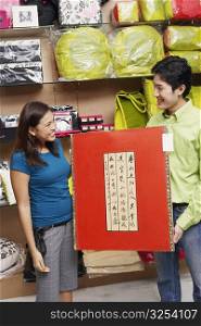 Young couple holding a painting and looking at each other in a store