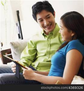 Young couple holding a picture frame and looking at each other on a couch