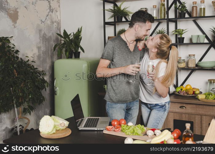 young couple holding champagne flute standing kitchen counter