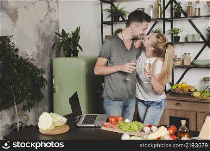 young couple holding champagne flute standing kitchen counter